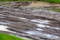 Dirty clay mud road with puddles and tire tracks - closeup with selective focus, diagonal composition Royalty Free Stock Photo