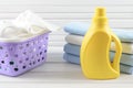 Dirty cloth in a plastic purple laundry basket, clean folded cloth and blank yellow detergent bottle on white wood background Royalty Free Stock Photo