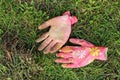 Dirty colored pink female garden gloves lie on the green grass