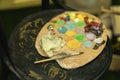 Dirty colorful artists palette on cardboard for mixing vibrant oil colors, dark wooden background. Art hobby, expression