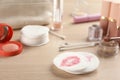 Dirty cotton pads, swabs and cosmetic products on wooden table