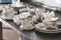 Dirty cups and plates with leftovers and silverware placed on metal table ready for dish washing in restaurant kitchen