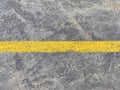 Dirty dark grey rugged concrete floor textured background with a yellow striped line
