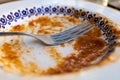 dirty decorated plate and fork after eating pasta with tomato sauce