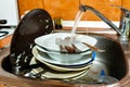 Dirty dishes in the kitchen sink, flowing tapwater Royalty Free Stock Photo