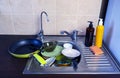 Dirty dishes in the kitchen in the sink - plates, spoons, a frying pan. Detergents and sponge for washing dishes Royalty Free Stock Photo
