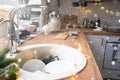 Dirty dishes in the sink in the garlanded kitchen, a holiday after a feast at Christmas. Mess after the guests for the New Year,