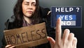 A dirty disheveled woman holds a cardboard sign with the text homeless. Female hand push a virtual button to the help