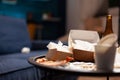 Dirty empty living room with food trash, bottle of beer and napkins on blue sofa Royalty Free Stock Photo