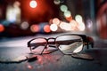 Dirty eyeglasses lying on street between shards with blurry night scene in background