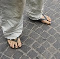 Dirty feet of a man wearing flip flops on the old stone floor. Royalty Free Stock Photo