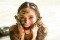 Dirty female model. Woman in clay mask laughs. Crazy girl in medical mud. Spa Outdoor. Happy dirty woman in Dead sea
