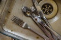 Dirty fork knife and spoon covered with icing under water inside kitchen sink Royalty Free Stock Photo