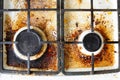 Dirty gas stove surface. Two gas burners and cast iron grate of a gas oven surrounded by old leftovers of food and drinks Royalty Free Stock Photo