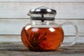 Dirty glass teapot with tea flower on old wooden table