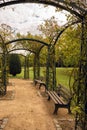 Dirty gravel road with  benches and arches in a park in autumn with yellow, green and red trees, vertical image Royalty Free Stock Photo