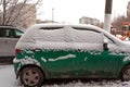 Dirty green compact car in the snow can not go. The first snowfall. cars covered in snow in the city. Transport problems, poorly Royalty Free Stock Photo