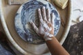 Dirty hand of potter in white clay on potter`s wheel Royalty Free Stock Photo
