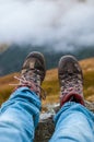 Dirty hiking shoes with mountains and clouds in the background