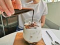 Dirty iced latte pouring espresso shot to white full cream cow milk in cozy coffee shop Royalty Free Stock Photo