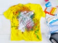 Dirty kids clothing is scattered on a white wooden table.Concept of searching for information on washing spots, the best means for