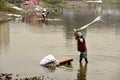 Dirty Laundry: Washerman wash clothes in polluted water Royalty Free Stock Photo