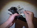 Dirty men hands hold in my hand an old battered wallet and purse burnt $ 100 bill on the background of the old wall Royalty Free Stock Photo