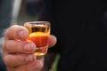 Dirty mens hand holding a shot glass with orange alcohol drink,