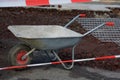 Dirty metal wheelbarrow behind a red-white caution tape Royalty Free Stock Photo