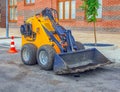 Dirty midget skid loader is parked at the construction site. Small bulldozer. Construction machinery. Working with a soil Royalty Free Stock Photo