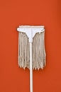 Dirty mop against on brown wall Royalty Free Stock Photo