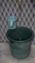 Dirty Plastic Bucket for water reservoir on a traditional bathroom with abstract cube wall pattern