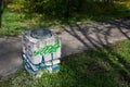 Concrete trash can with graffiti in green grass in park.