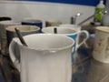 Dirty mugs on a sink draining board with teaspoons in