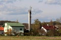 Dirty old concrete industrial chimney filled with cell phone antennas and transmitters rising above family houses Royalty Free Stock Photo