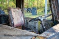 Dirty old driver`s seat and steering wheel in a rusty bus with broken windows and with traces of paint in a forest. Bunker Royalty Free Stock Photo