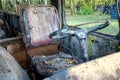 Dirty old driver`s seat with yellow leaves and steering wheel in a rusty bus with broken windows and with traces of paint Royalty Free Stock Photo