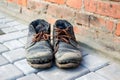 Dirty old shoes on paveng floor. A pair of dirty boots. Old worn leather shoes with variegated brown laces. The concept Royalty Free Stock Photo