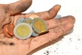 A dirty palm carrying coins on the white floor background.