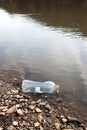 Water pollution. Plastic bottle on the river beach. Royalty Free Stock Photo
