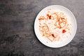 Dirty plate with food leftovers on grey background, top view