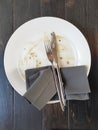 Dirty plate with fork and knife on wooden table after dinner Royalty Free Stock Photo