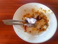 Dirty plates and dirty spoons filled with leftover food and used tissues on the restaurant table.