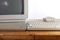 Dirty retro computer system on old pine desk. Outdated computing