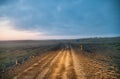 Dirty road at sunset illuminated by car lights Royalty Free Stock Photo