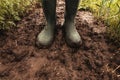 Dirty rubber boots in muddy soil, farmer standing in field after rain Royalty Free Stock Photo