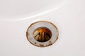 Dirty and rusty washbasin, close up view. Metal drain hole with red rust stain. Corrosion, unsanitary. Stained bathroom Royalty Free Stock Photo