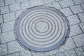 Gray sewer hatch with pattern for drainage on the sidewalk