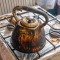 Dirty smoked kettle stands on a gas stove