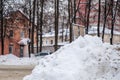 Dirty snowdrift by the road against the backdrop of city houses and trees. Royalty Free Stock Photo